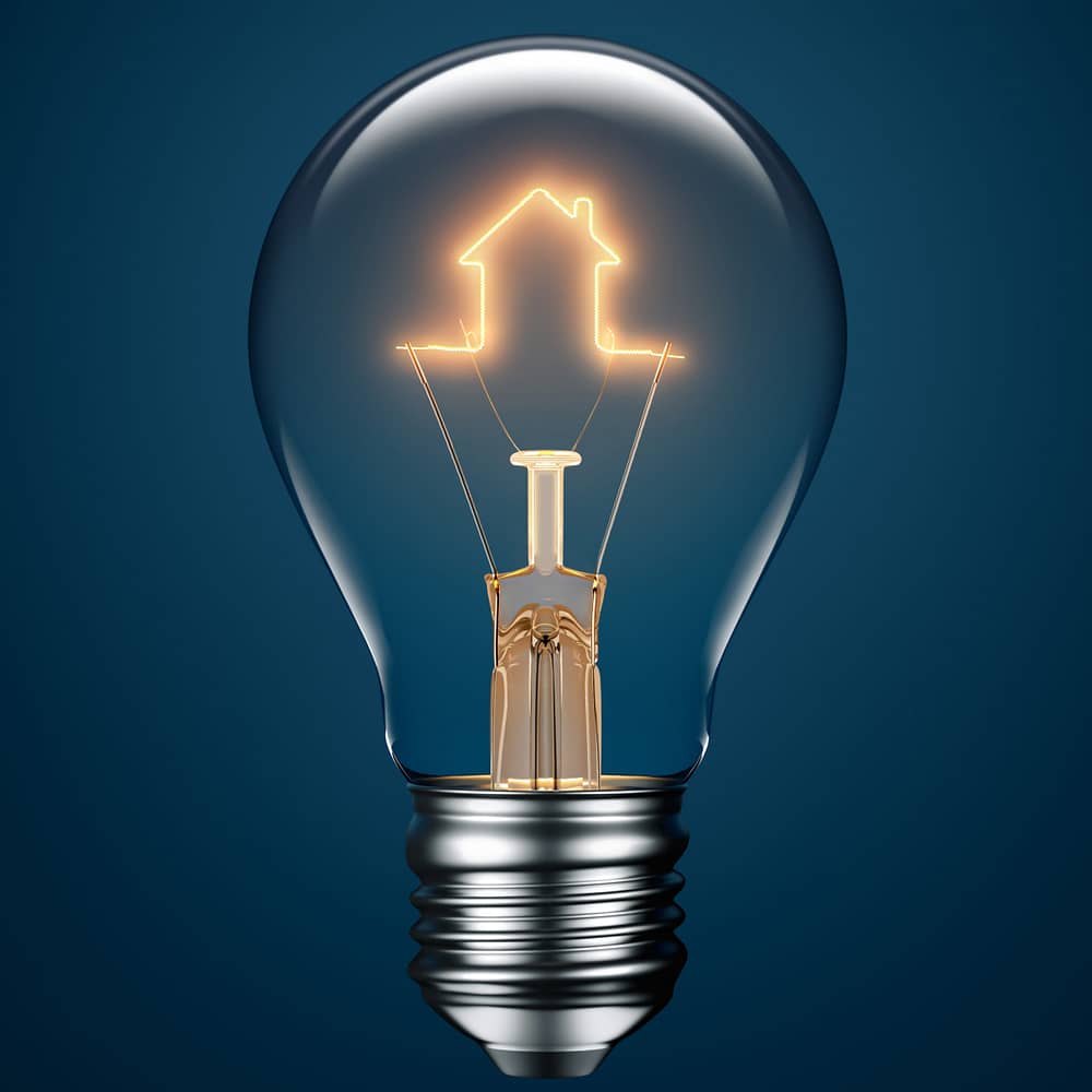 Light bulb with filament forming a house icon on blue background